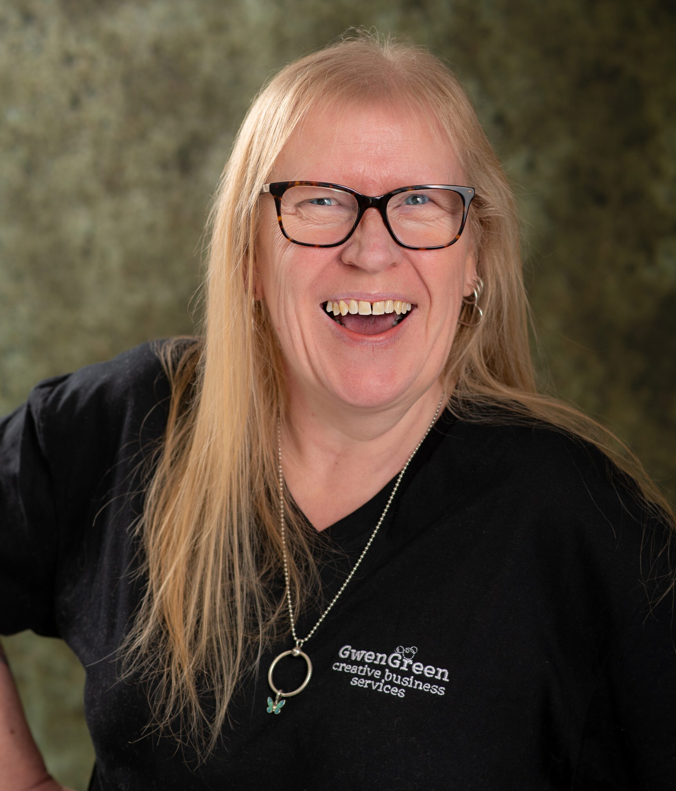 Jackie Lehane of GwenGreen CBS Jackie Lehane, founder of GwenGreen Creative Business Services, wearing a black t-shirt showing the GwenGreen branding, and laughing at the camera